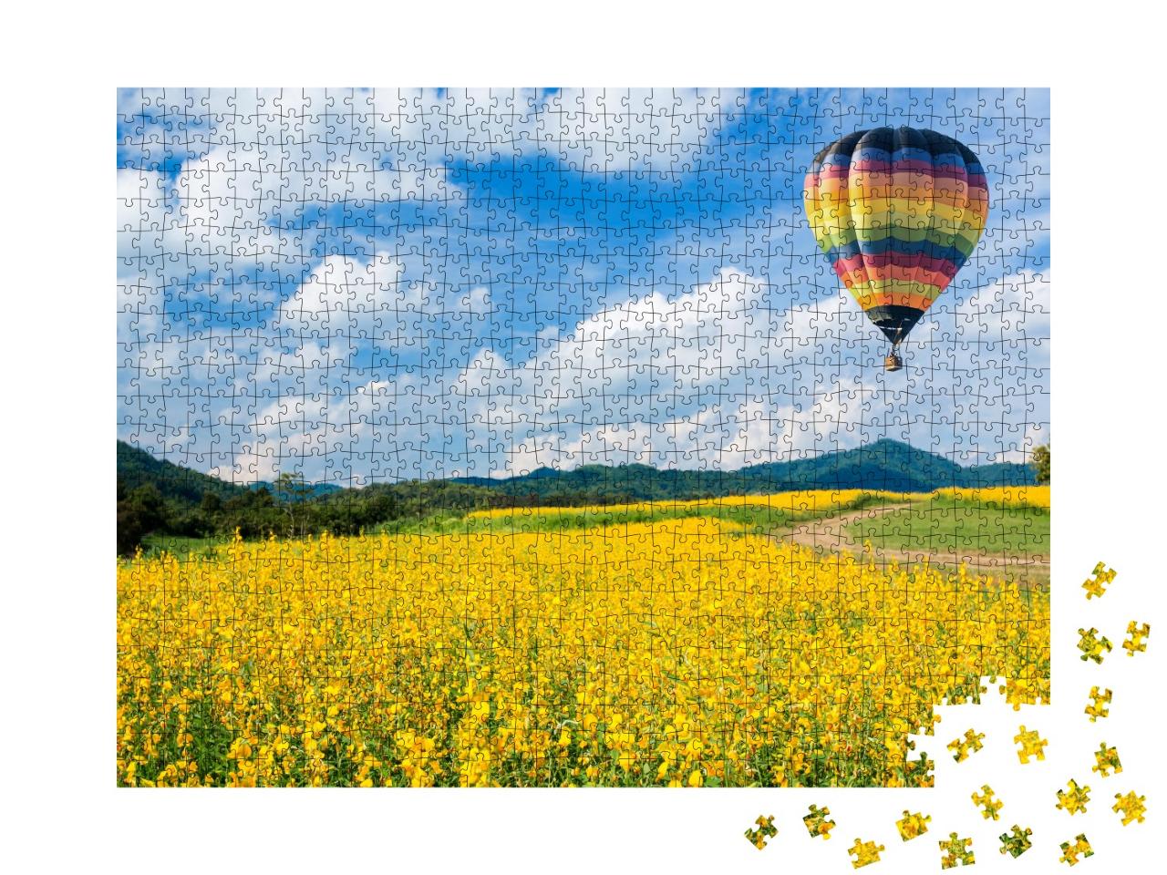 Puzzle 1000 Teile „Heißluftballon über gelben Blumenfeldern, im Hintergrund ein Mittelgebirge “