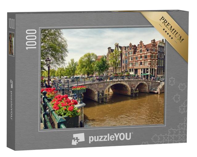 Puzzel 1000 stukjes „Drievoudige boogbrug in Amsterdam met geraniumbloesems tussen de grachten“