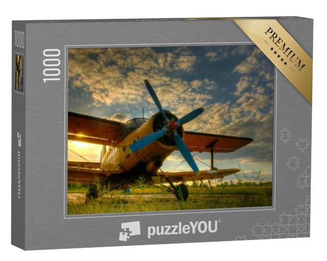 Puzzel 1000 stukjes „Historisch vliegtuig op groen gras bij zonsondergang“